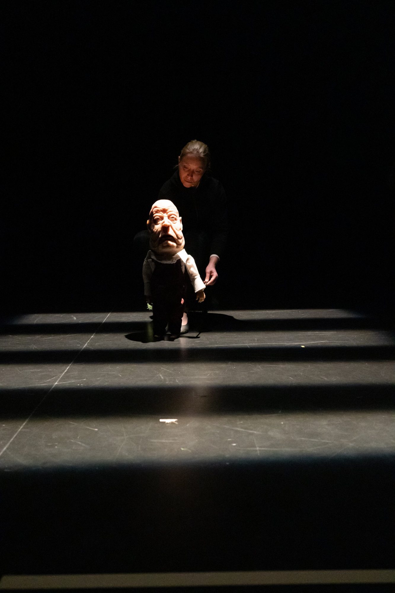 Une interprète guide la marionnette du vieux philosophe dans des bandes de lumière
