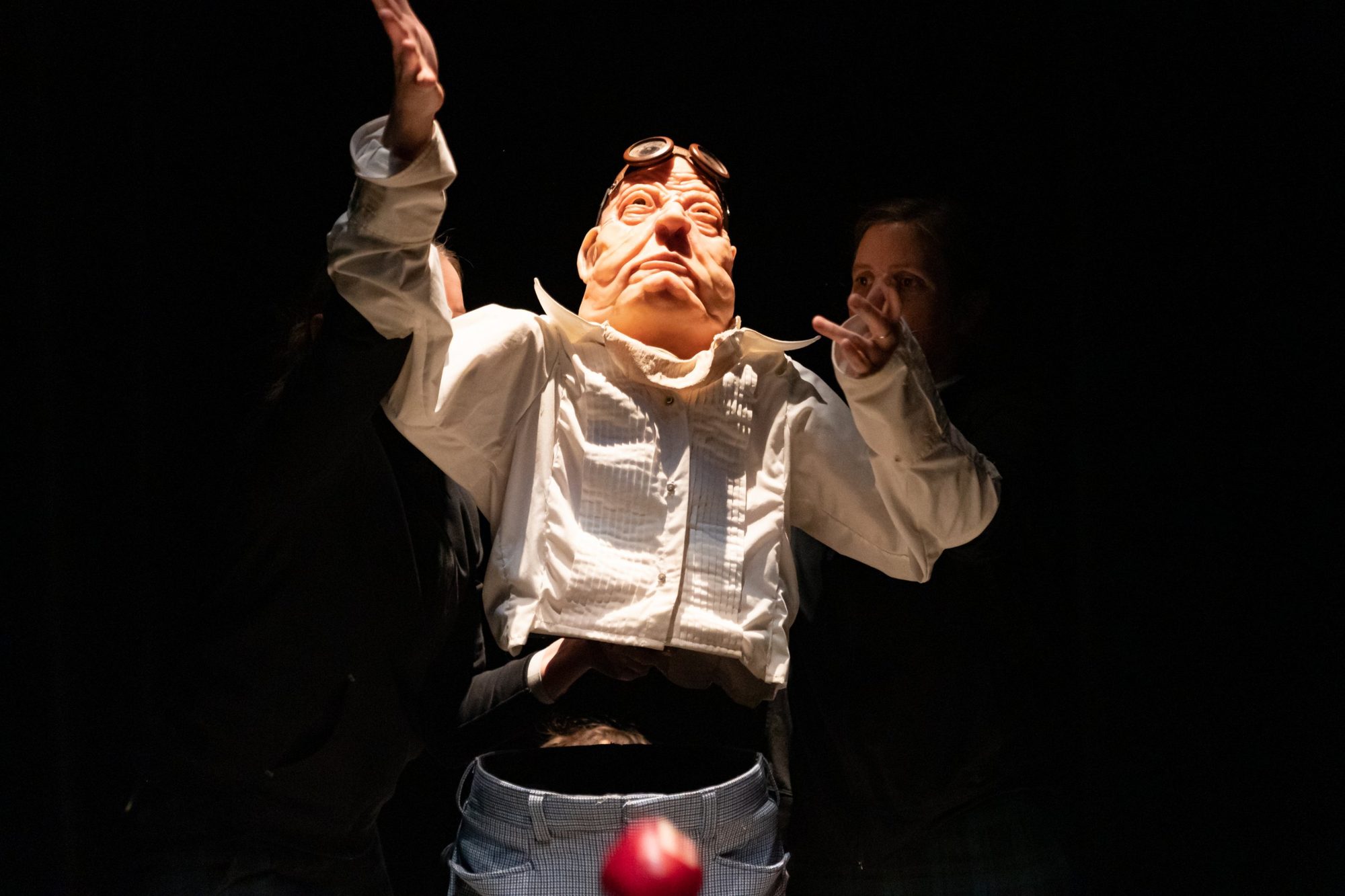 La marionnette du vieux philosophe lève les bras, une pomme rouge tombe au premier plan